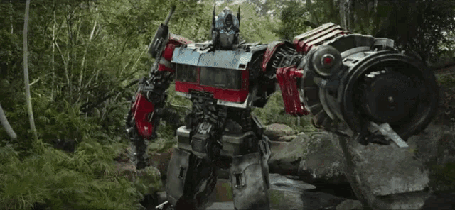 a transformer is standing in the middle of a forest with trees in the background .