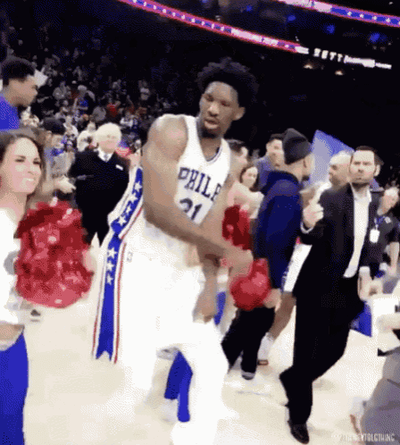 a basketball player from the philadelphia 76ers is dancing on the court with fans .
